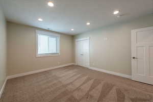 Unfurnished bedroom featuring light carpet, recessed lighting, a closet, and a textured ceiling