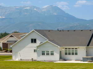 Rear view of house with a mountain view, a yard, and a hot tub