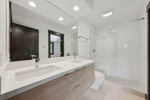 Bathroom with double vanity, tiled shower, and recessed lighting