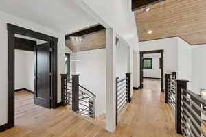 Corridor with an upstairs landing, wood finished floors, lofted ceiling, and recessed lighting