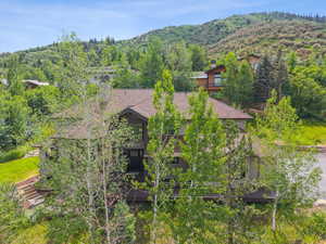 Aerial view of property and surrounding area featuring a mountain backdrop and a heavily wooded area