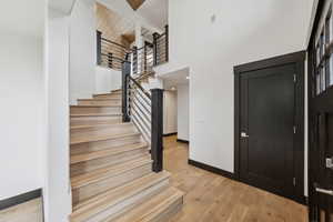 Entrance foyer with stairs, light wood-type flooring, and a towering ceiling