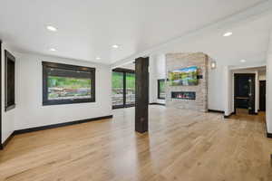 Unfurnished living room with a stone fireplace, light wood-type flooring, and recessed lighting