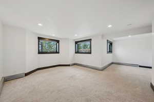 Empty room with light carpet and recessed lighting