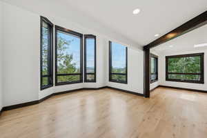 Unfurnished room featuring light wood-type flooring, recessed lighting, and beam ceiling