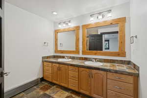 Bathroom with double vanity and stone tile flooring