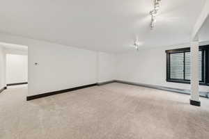 Carpeted spare room featuring baseboards and track lighting