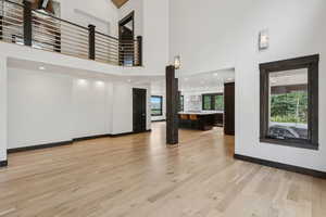 Unfurnished living room featuring light wood finished floors and a high ceiling