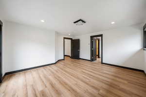 Empty room with light wood finished floors and recessed lighting