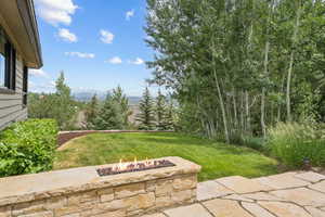 View of green lawn featuring a fire pit and a patio area