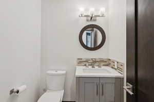 Half bath featuring vanity and backsplash
