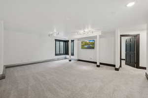 Carpeted empty room featuring baseboards and track lighting