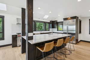 Kitchen featuring high quality appliances, a skylight, tasteful backsplash, custom exhaust hood, and light stone countertops