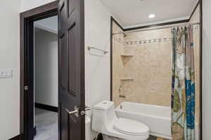 Bathroom featuring toilet and shower / bath combination with curtain