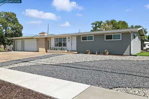 Ranch-style home featuring an attached garage, concrete driveway, and a chimney
