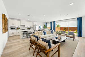 Living area with recessed lighting and light wood-style floors - pic of model home of same floor plan, actual home may vary slightly on flooring, colors, cabinets, etc.