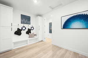 Mudroom featuring attic access and light wood-style flooring. pic of model home of same floor plan, actual home may vary slightly on flooring, colors, cabinets, etc.