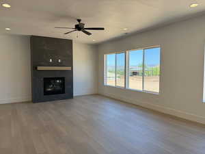Unfurnished living room with wood finished floors, recessed lighting, a ceiling fan, and a fireplace