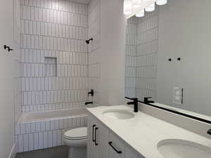 Bathroom featuring double vanity, tile patterned flooring, and tiled shower / bath