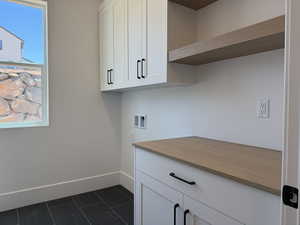 Washroom with cabinet space, hookup for a washing machine, and dark tile patterned floors