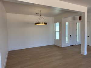 Spare room with wood finished floors and a chandelier