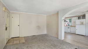 Carpeted living room with arched walkways and crown molding