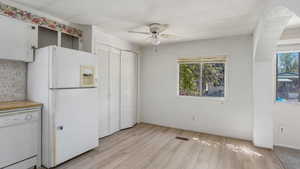 Kitchen with white appliances, a ceiling fan, light wood finished floors, crown molding, and light countertops