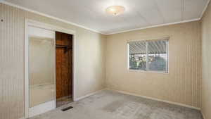 Bedroom with ornamental molding, carpet, a closet, and wallpapered walls