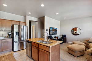 Kitchen with appliances with stainless steel finishes, open floor plan, light stone countertops, recessed lighting, and a center island with sink