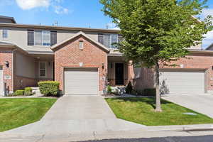 Traditional-style home featuring concrete driveway, a front yard, brick siding, and a garage