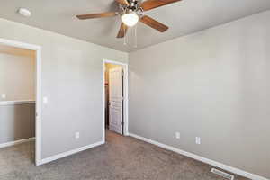Unfurnished bedroom featuring carpet, a walk in closet, and ceiling fan