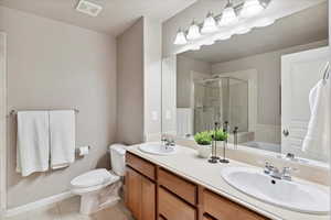Bathroom featuring a shower stall, tile patterned flooring, double vanity, and a garden tub