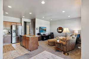 Kitchen featuring appliances with stainless steel finishes, open floor plan, light stone counters, recessed lighting, and a kitchen island with sink