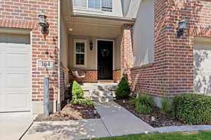 Doorway to property featuring brick siding, a garage, and stucco siding