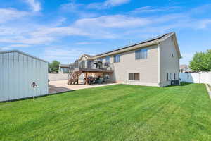Rear view of house featuring a patio, a fenced backyard, a wooden deck, stairway, and a storage shed