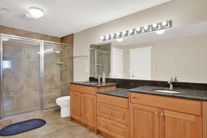 Bathroom featuring double vanity, a shower stall, and tile patterned floors