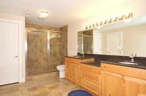 Full bath with double vanity and a shower stall
