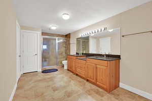 Full bathroom with double vanity and a shower stall