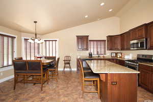 Kitchen featuring stainless steel appliances, a chandelier, a center island, recessed lighting, and light stone countertops