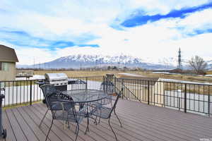 Wooden terrace featuring a mountain view, outdoor dining area, and a grill