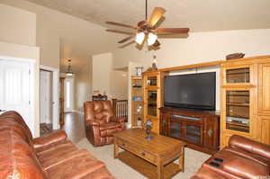 Living room with ceiling fan and lofted ceiling