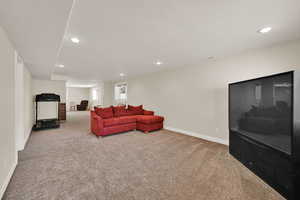 Carpeted living area with baseboards and recessed lighting