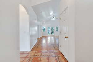 Hallway featuring arched walkways, high vaulted ceiling, and light tile patterned floors