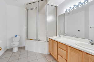 Bathroom with double vanity, tile patterned floors, and enclosed tub / shower combo