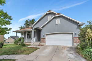 View of front of home featuring stucco siding, an attached garage, concrete driveway, and brick siding
