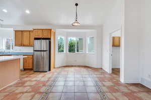 Kitchen featuring freestanding refrigerator, light countertops, pendant lighting, dishwasher, and recessed lighting