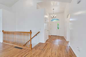 Entrance foyer with wood finished floors, a chandelier, a towering ceiling, and arched walkways