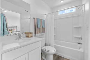 Full bathroom with shower / bathtub combination with curtain, vanity, and wood finished floors