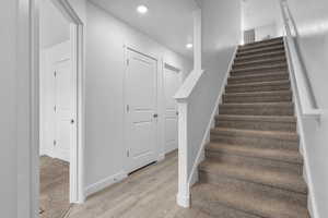 Stairway with wood finished floors and recessed lighting