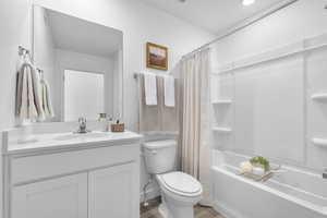 Bathroom with wood finished floors, vanity, and shower / tub combo with curtain